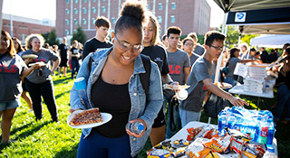 student smiling while she holds a plate of food