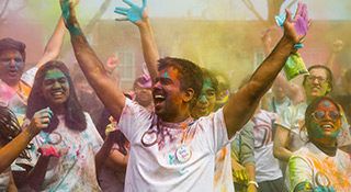 uno students attending holi festival covered in bright colored powders